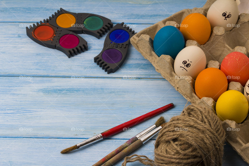 Easter eggs,  rope roll and paint tools on blue wood background