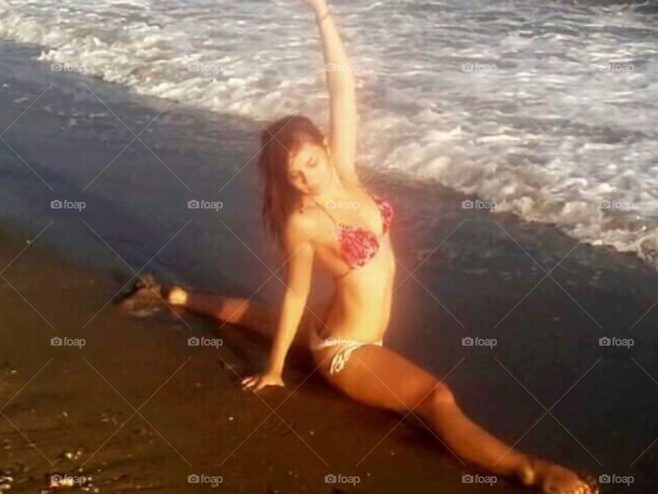 Woman in bikini stretching near the coast