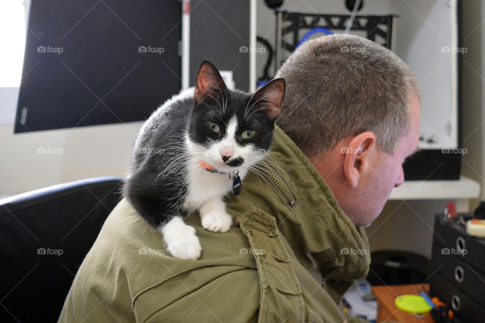 Black and white cat sitting on man's back.