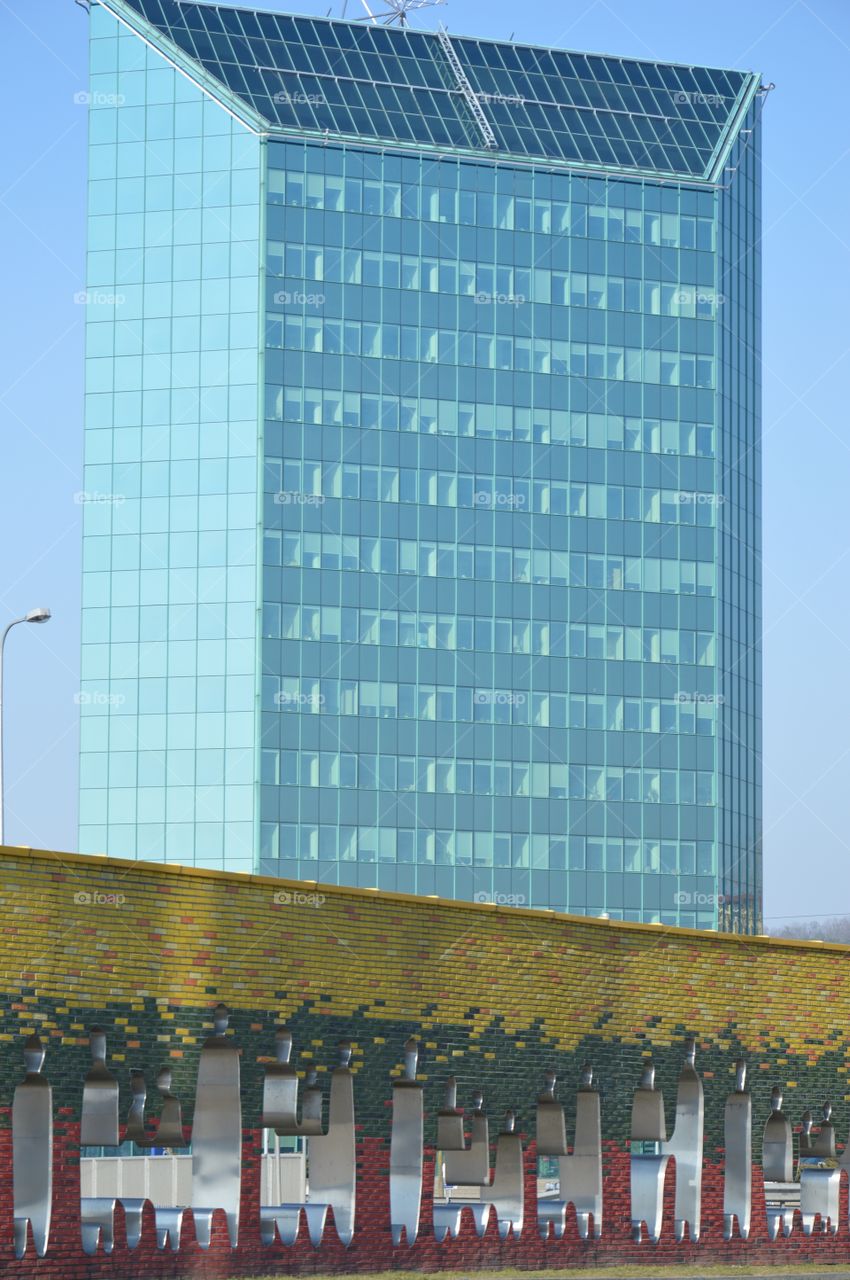 Glass building and monument in one photo. Vilnius