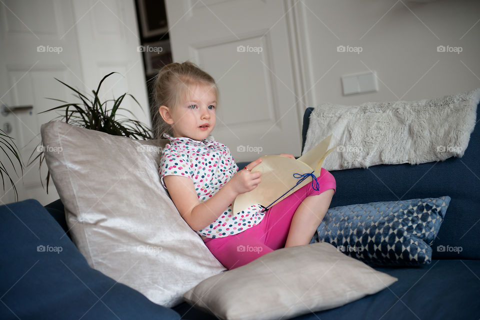 Cute girl reading a notebook at homebon the couch