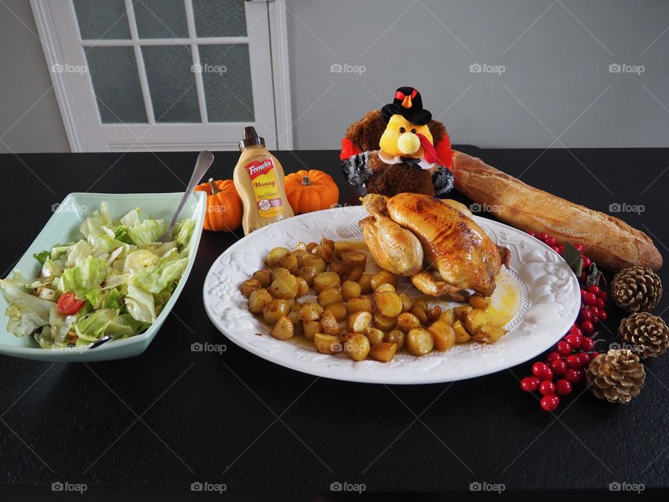 Roast chicken and potatoes with salad and baguette accompanied by an assortment of French’s mustards and a Thanksgiving decor.