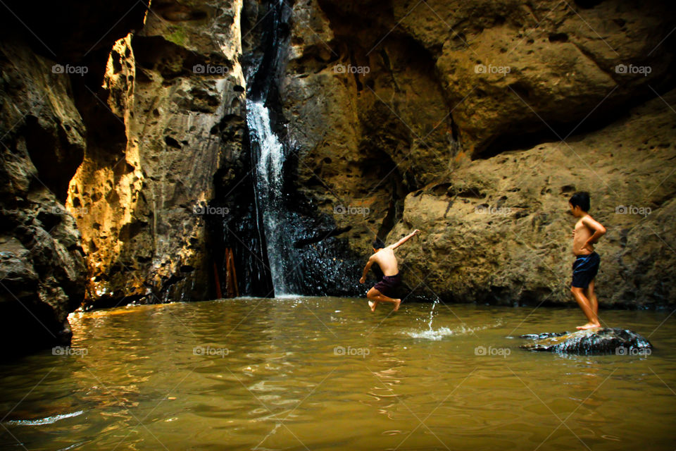 Two boys play together joyfully waterfall.