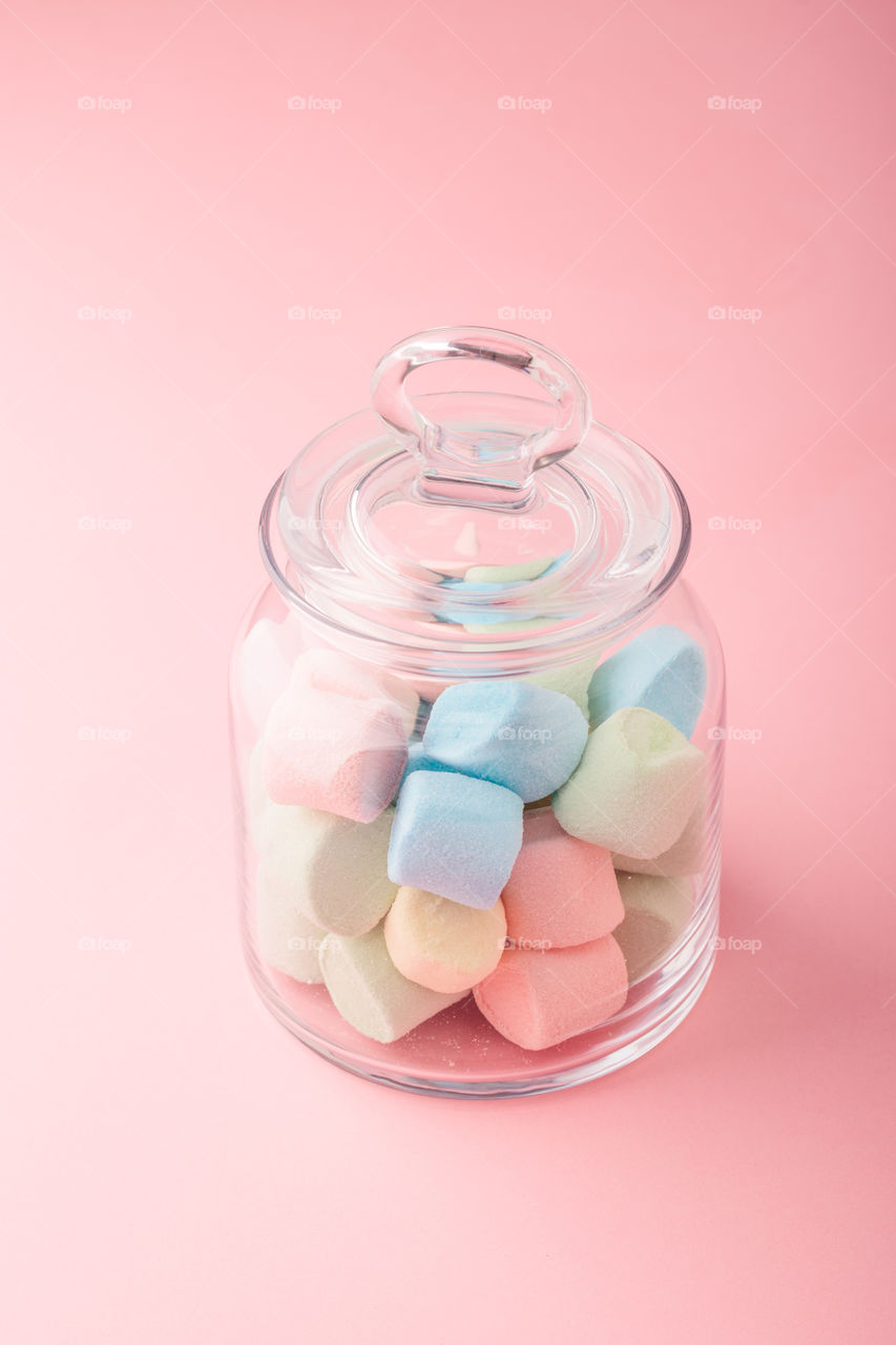 Jar filled with colorful marshmallows on plain background