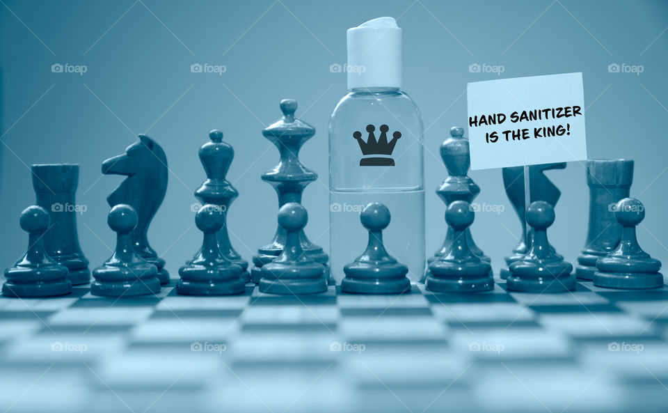 Coronavirus concept image chess pieces and hand sanitizer on chessboard illustrating global struggle against novel covid-19 outbreak.