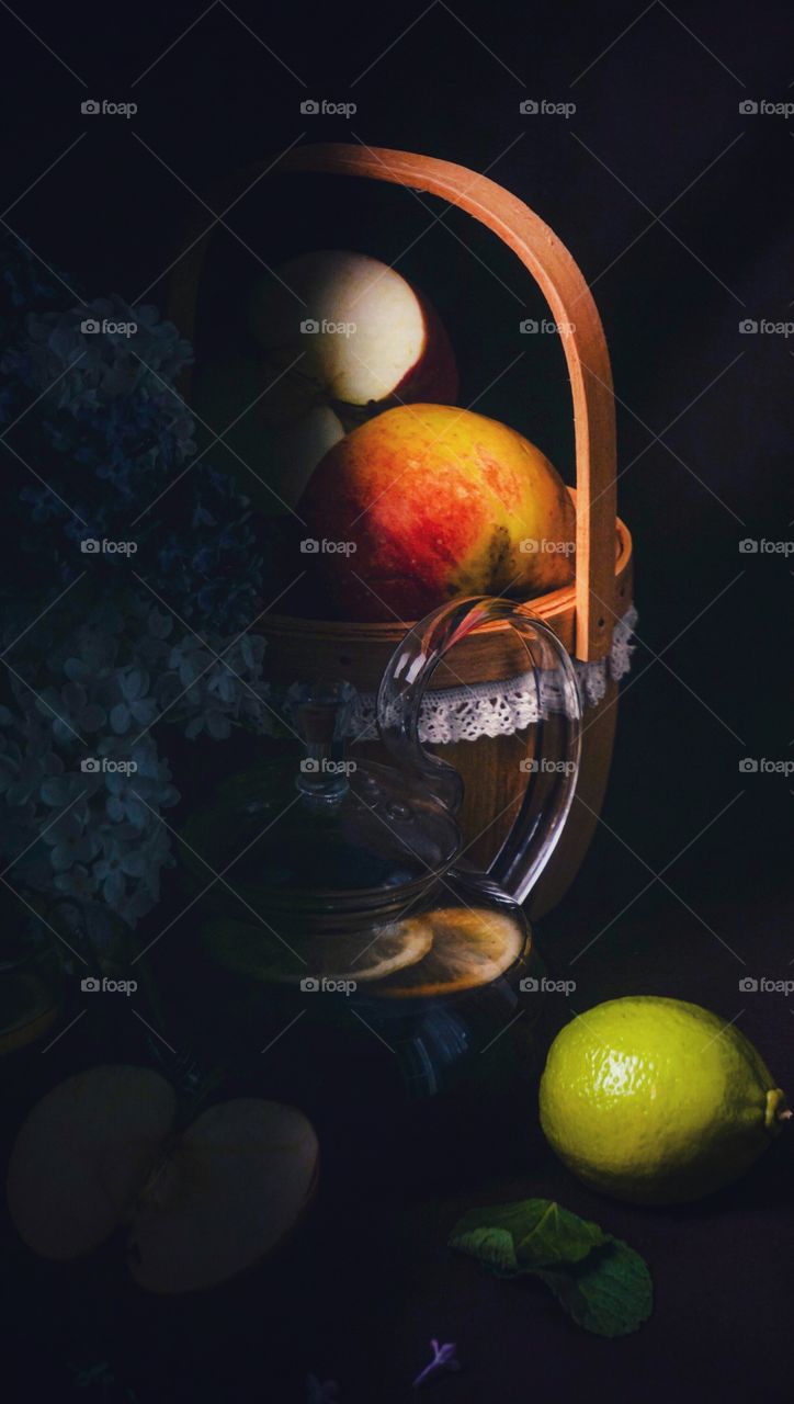still life of apples, lilac, lemon and lime on a dark background