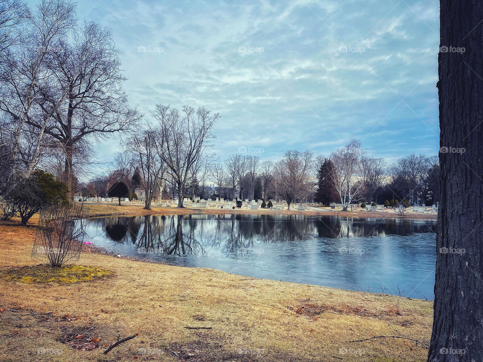 Ice and reflection on a pond in a New England cemetery 