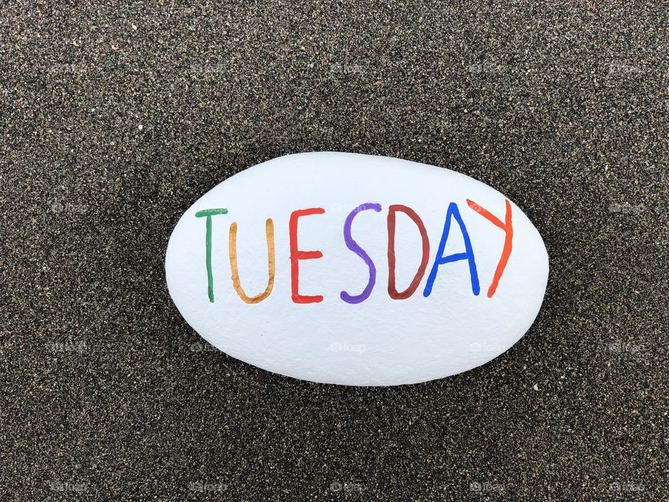 Tuesday, second day of the week carved and colored on a stone over black volcanic sand