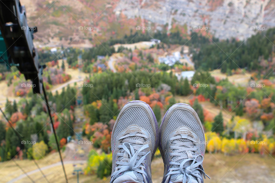 My feet hanging from a cable lift with fall colors in the background 