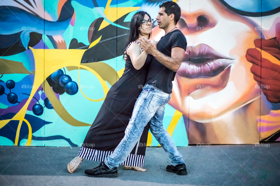 Young Couple Dancing In The Street In Front Of Graffiti Wall
