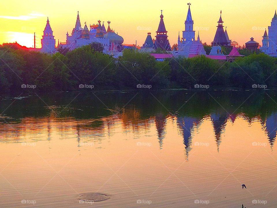Sunset. On the water of the river, reflections of the towers of domes and trees. The domes of the towers at sunset were painted in different shades of purple. Peace and tranquility of nature