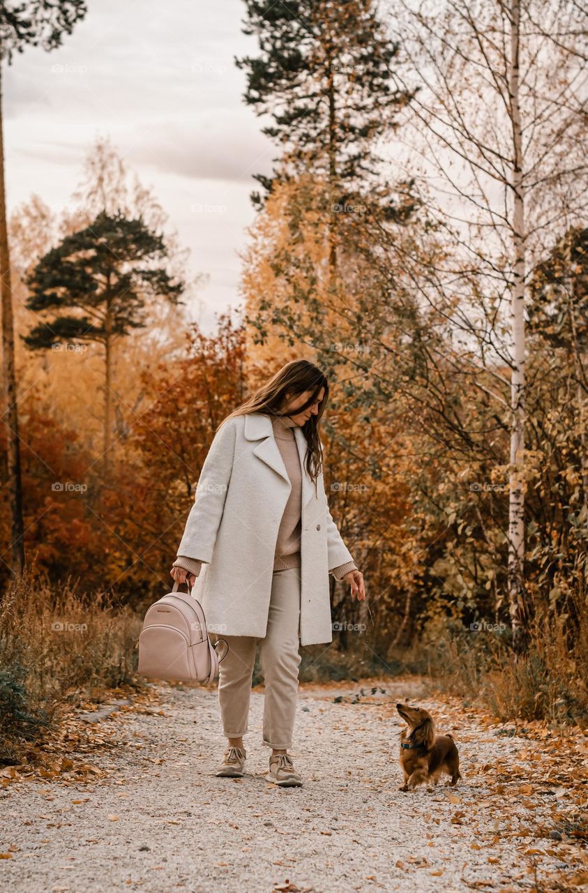 Autumn in the park a girl walks with a pet rabbit dachshund