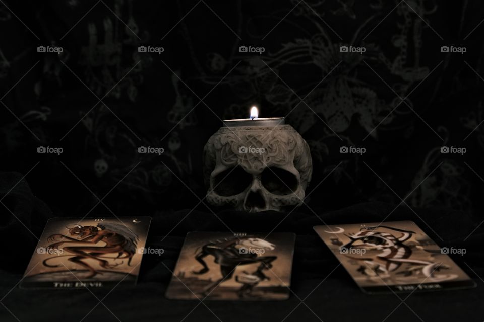 Skull with candle and tarot cards in dark background