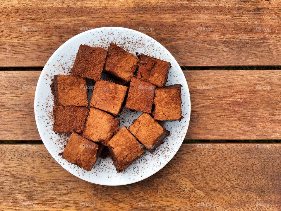 Chocolate brownies on a white plate on a wooden table