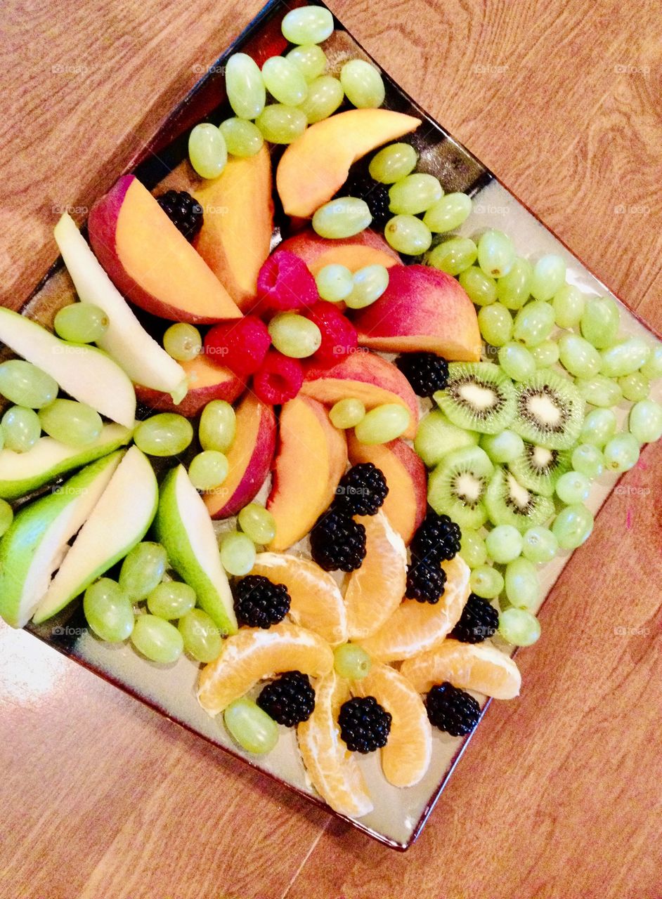 A large plate of delicious colorful fruit consisting of green apples, oranges, peaches, blackberries, kiwi, and grapes! 