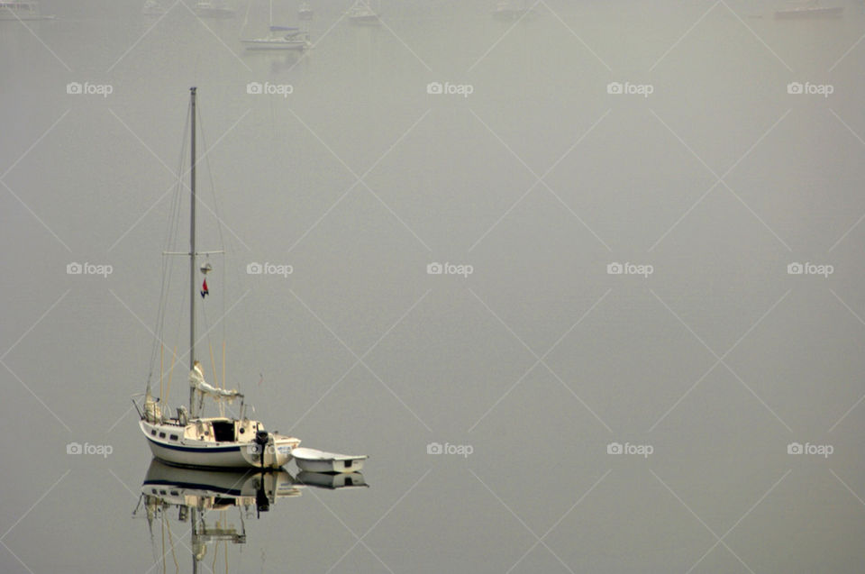 Sailboat sits on the serene calm bay on a foggy morning