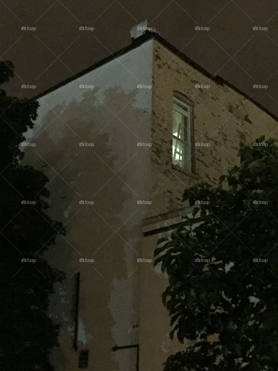 White brick building with light in a window 