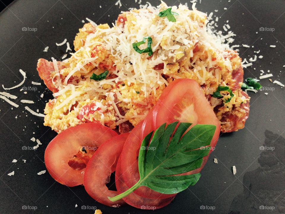Scrambled egg with sausage, parmesan cheese and tomato