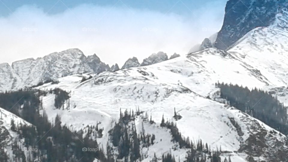 The snow covered mountain peaks against the bright sky of the Colorado Rocky Mountains.