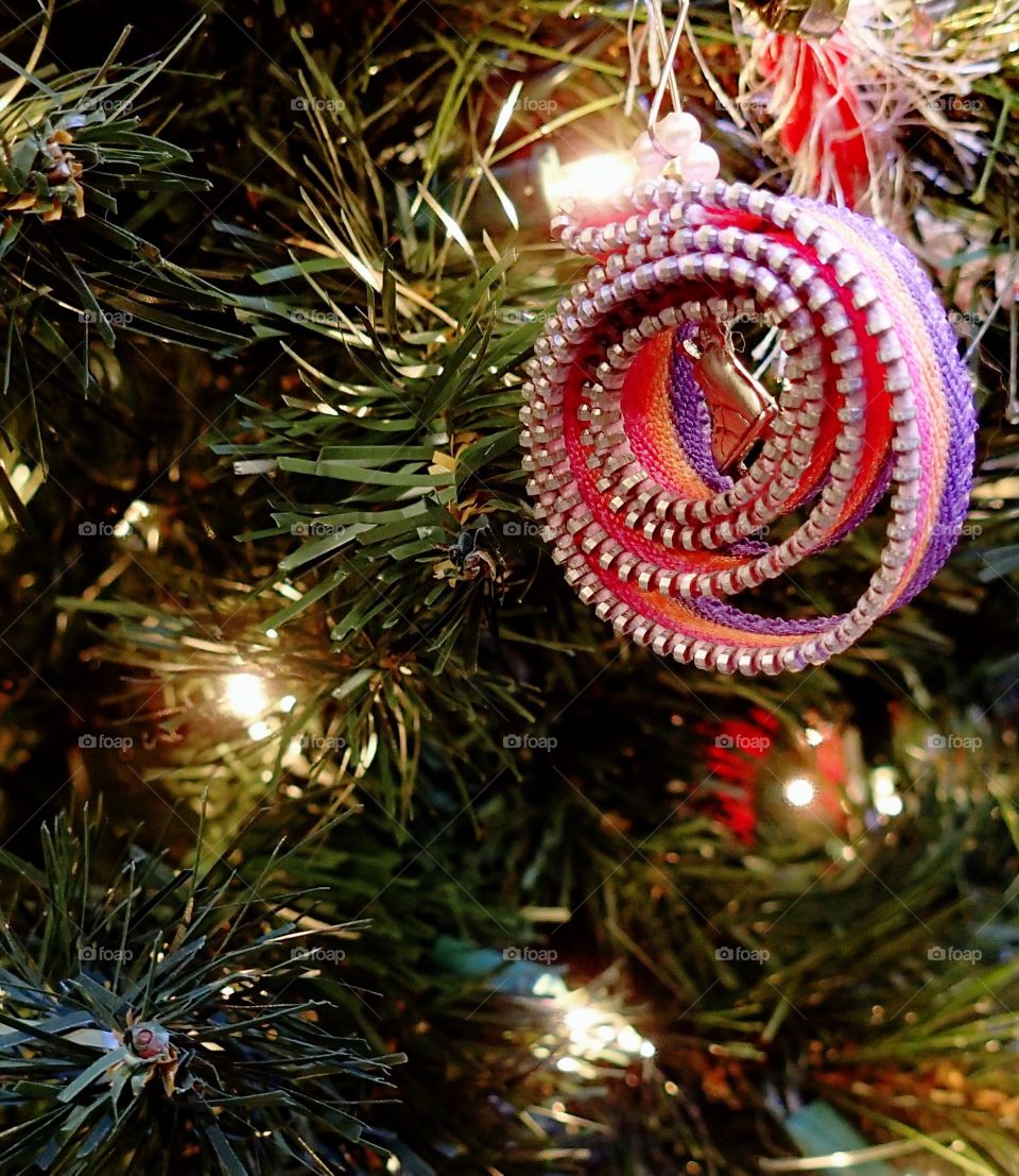 A unique curled Christmas ribbon ornament hanging from a tree. 