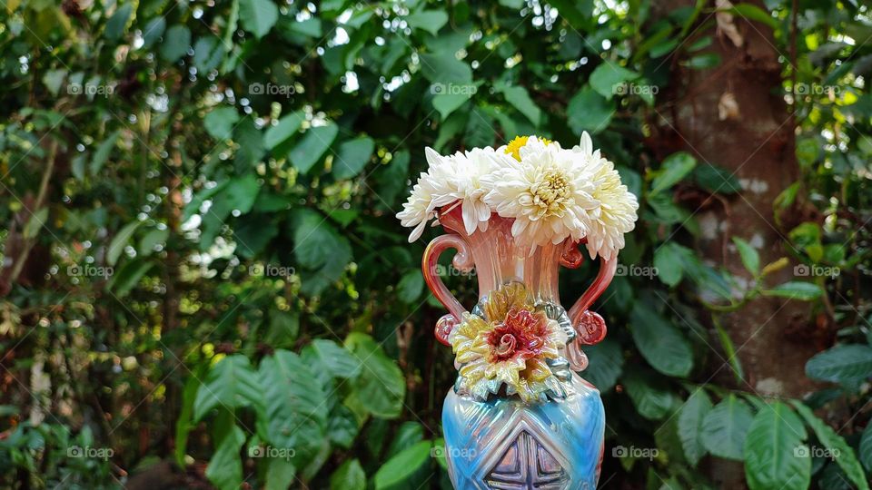 Beautiful white flowers in a colourful flowerpot with a flower sculpture, Flowers in a vase, colourful vase, white flowers in a vase