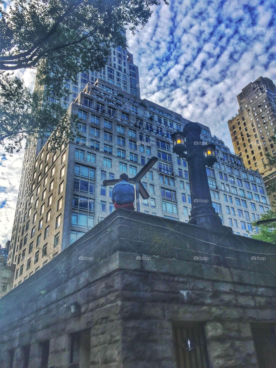 On The Edge. A man sitting on the edge just outside Central Park