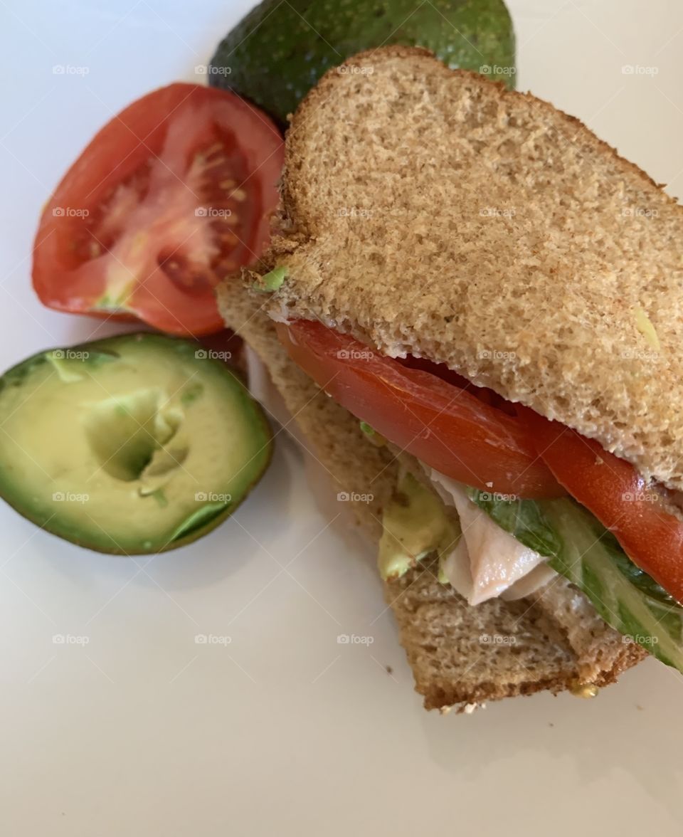 Homemade turkey sandwiches with avocado, tomatoes and lettuce on whole wheat bread 