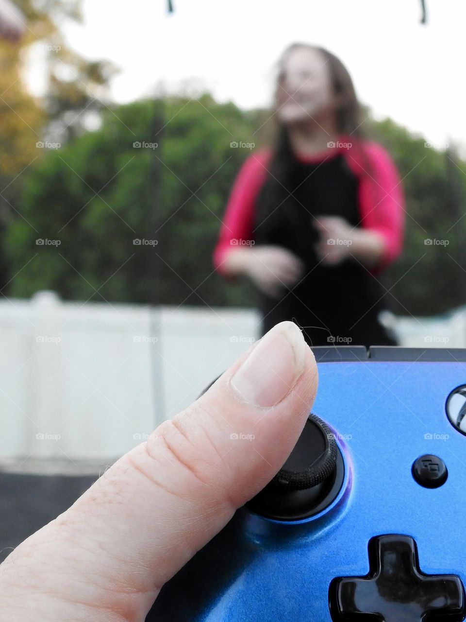 Xbox purple blue colored remote accessory used as if the mother is playing a game called: bring the children on the trampoline and play outside.