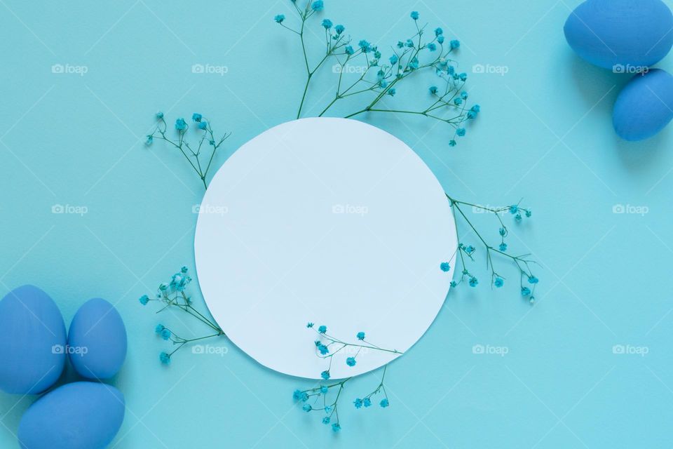 Flat lay mockup with blue eggs and small twigs of blooming flowers placed around empty white circle