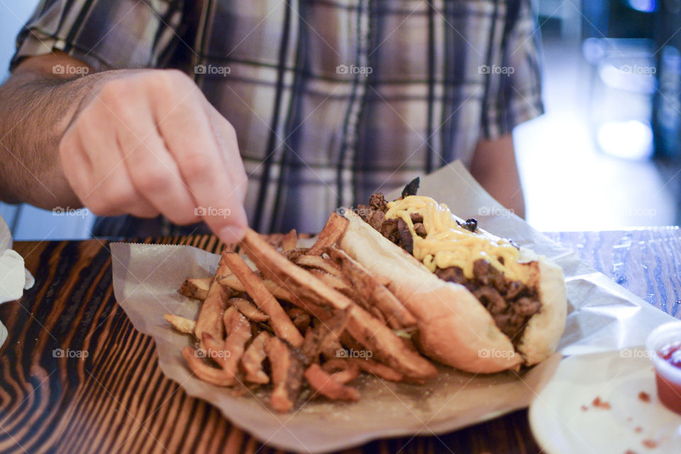 Man with cheesesteak and fries