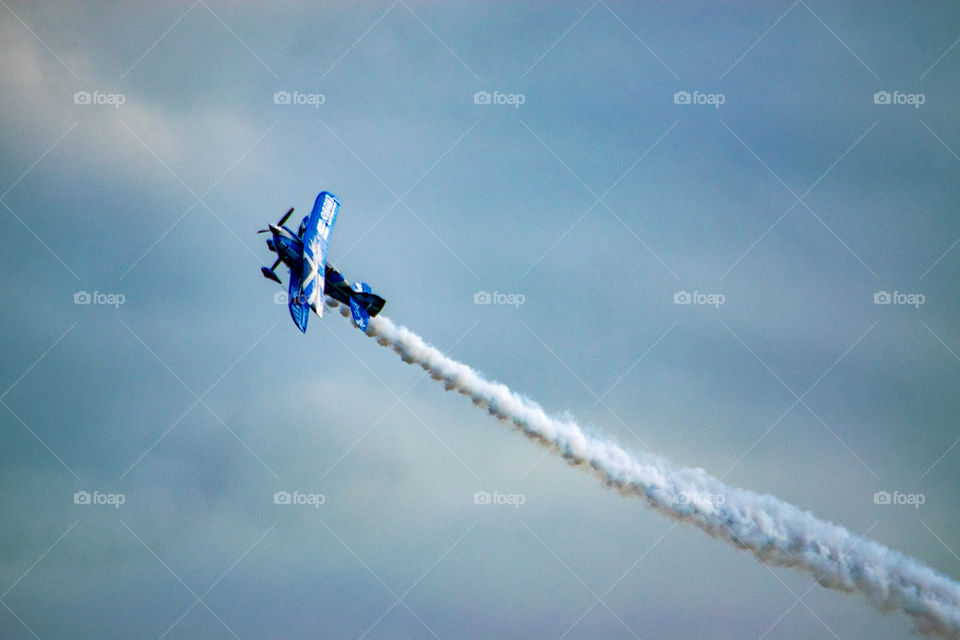 Stunt biplane with vapor trail in the evening sky