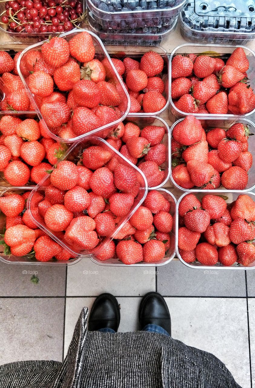 Looking down at strawberries. Looking down at fresh red fruit (strawberries and redcurrand ) in plastic baskets for sale at the market.