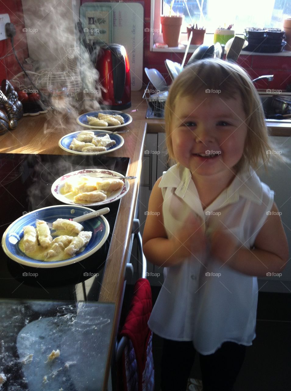 Happy girl standing with plate in kitchen