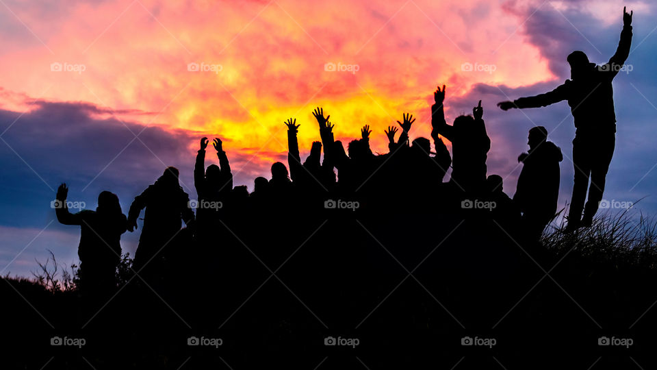 silhouette, group of happy people jumping in sunset