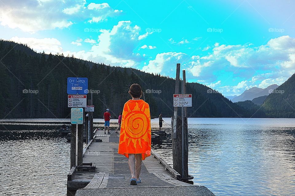 Swimming off the dock, freshwater mountain lake. Fellow walking down dock wearing orange beach towel