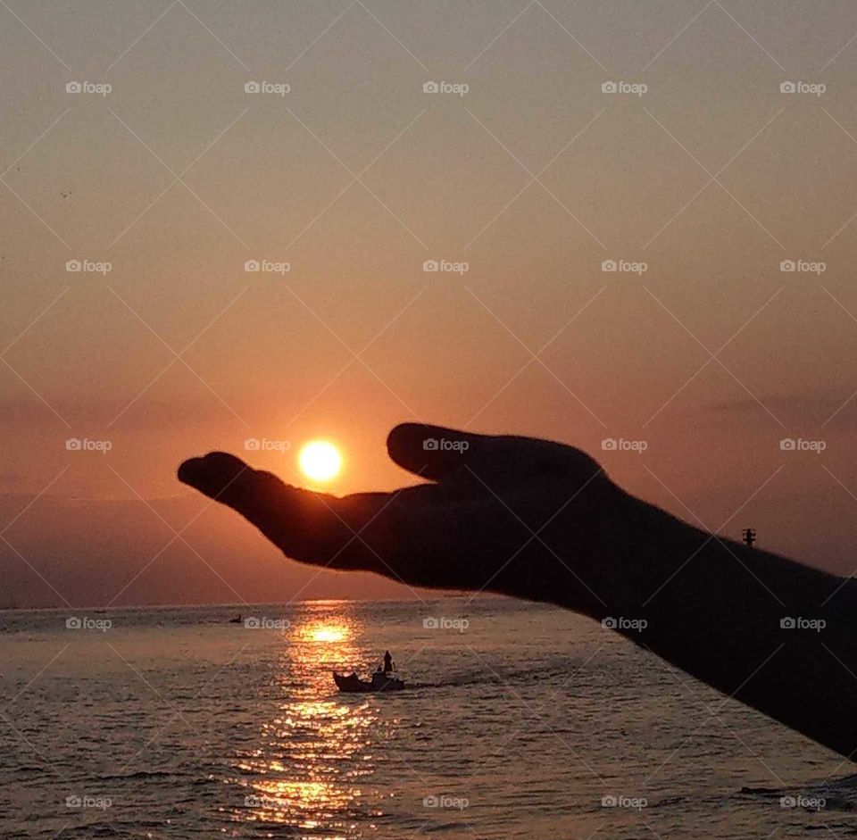 Light: natural vs artificial. an island's sunrise at seashore and a fishingboat just go fishing. a beautiful reflection.