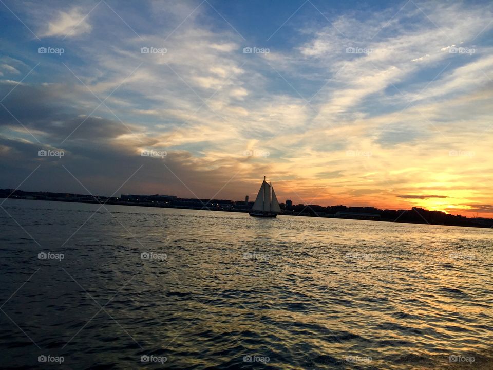 Sailboat on water at sunset sky reflecting 