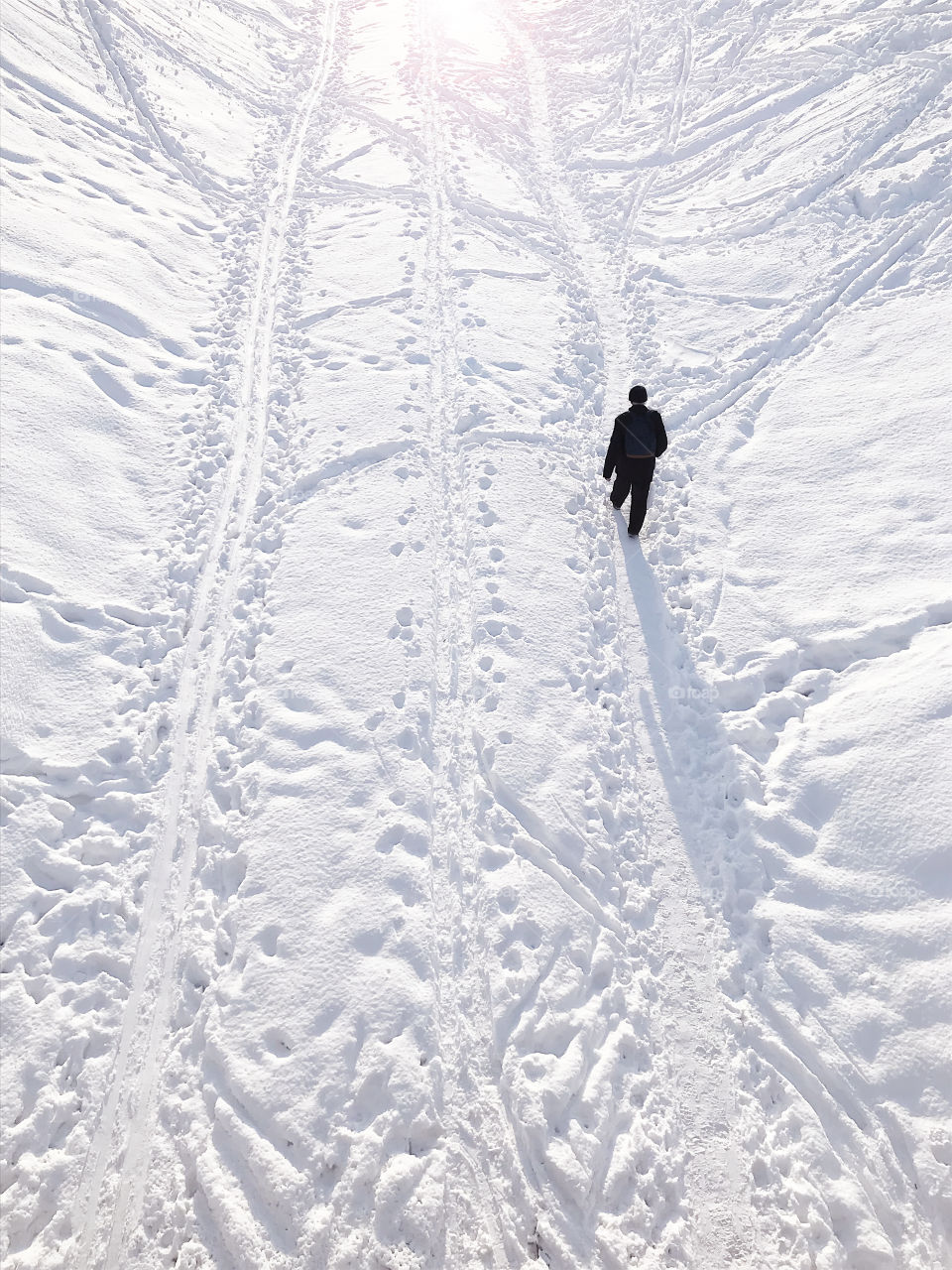 Aerial view of a Silhouette of a human walking by the white snow covered land 