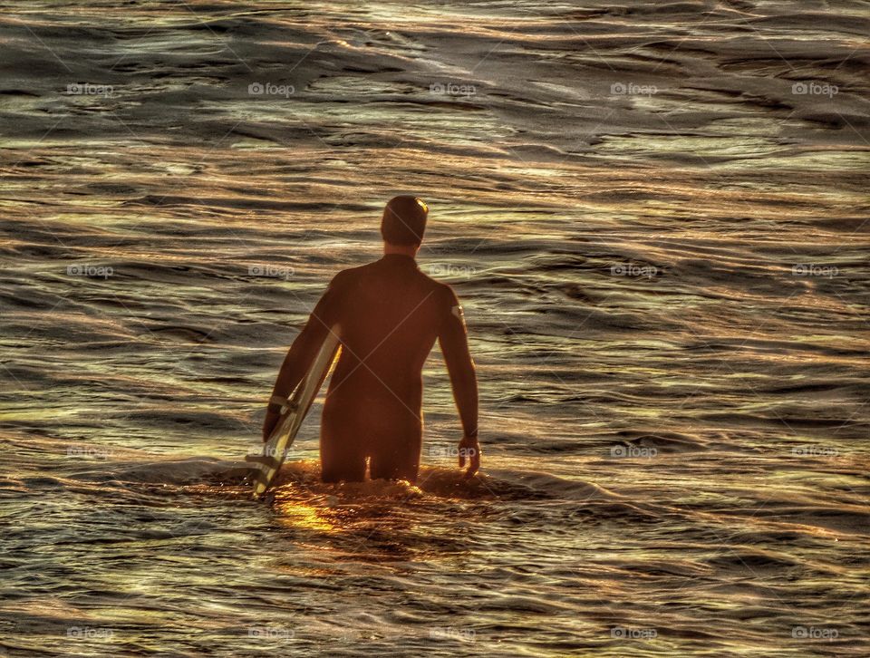 Surfer entering the waves at sundown in Half Moon Bay, California
