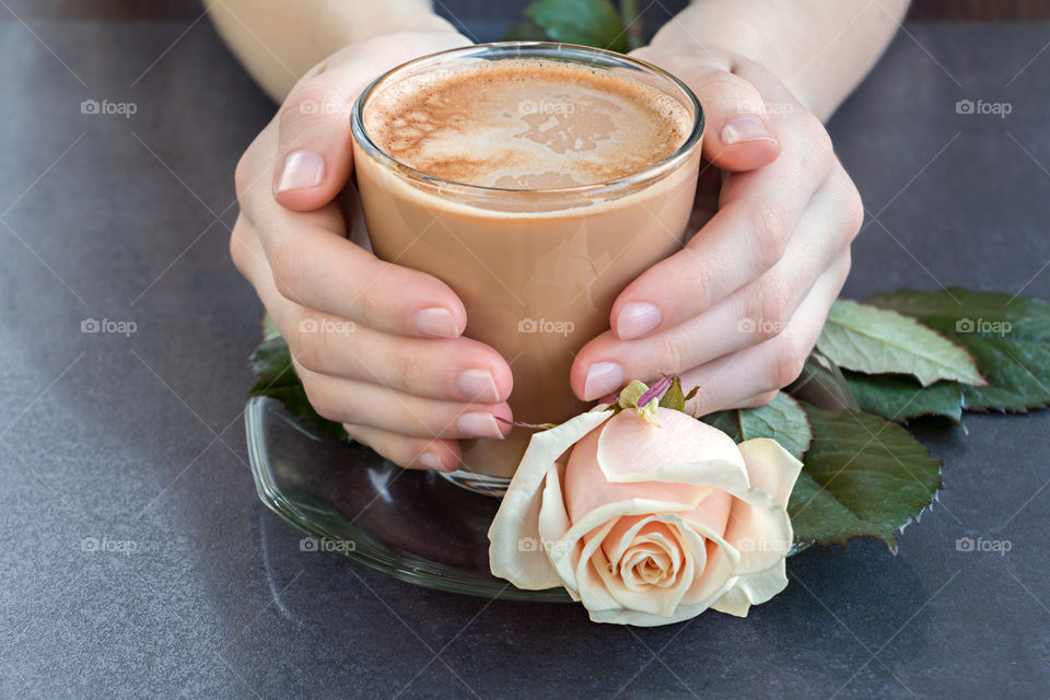 Coffee in hands with rose