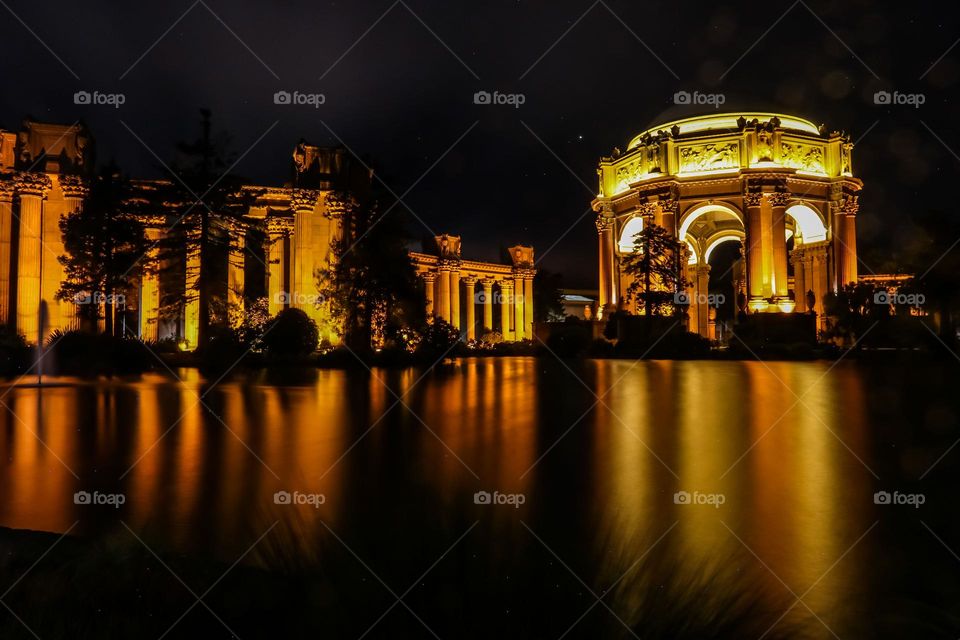 Palace of Fine Arts in San Francisco California at night reflecting the lights of this landmark structure on a calm evening in the lagoon with the faint stars of the night sky