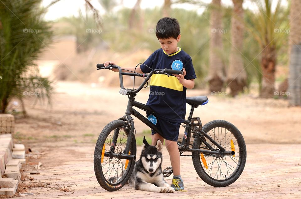 boy on a bicycle and a puppy sitting under it