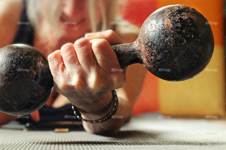 Close-up of a woman's hand lifting a rusty dumbbell