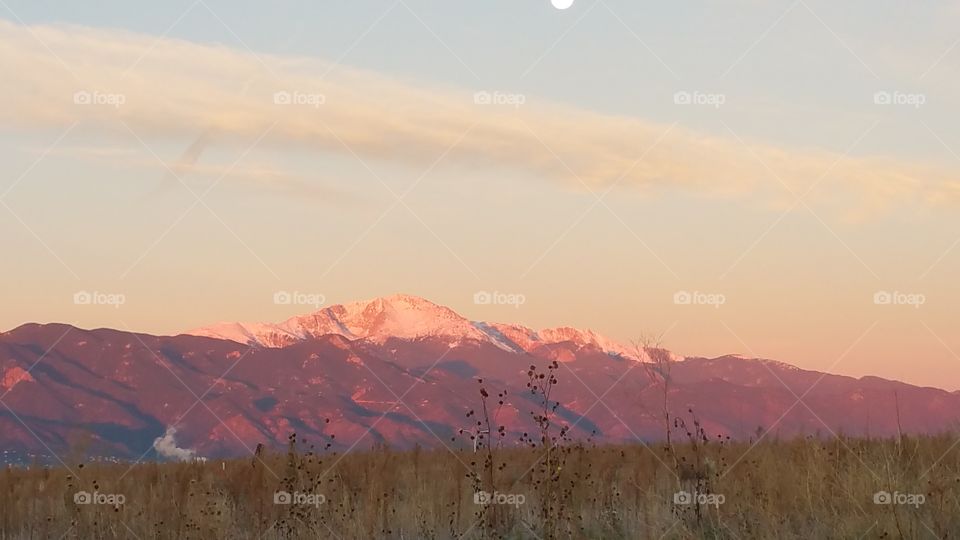 Pink Sun on Snow Capped Mountains, Colorado Springs.  Cloudy Sky.