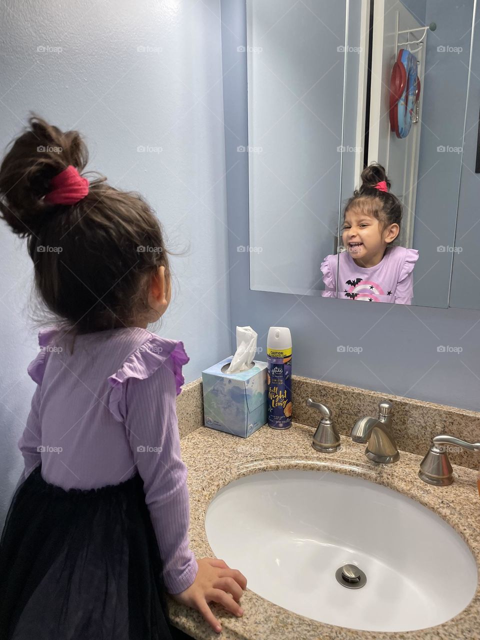 Little girl looks at herself in the mirror, posing in the mirror, positive self affirmations in the morning time, telling yourself positive thoughts