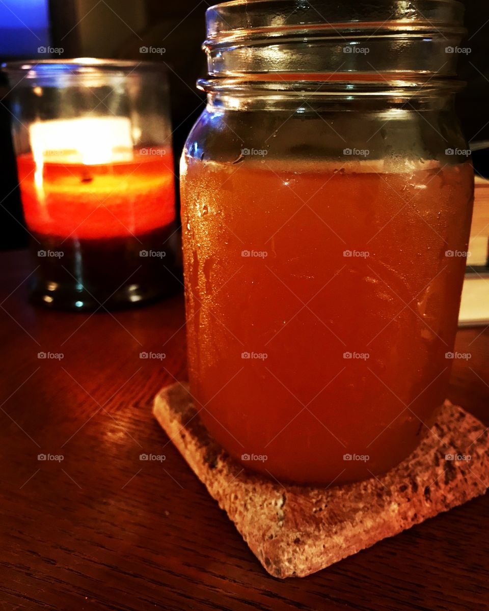 Apple cider in a mason jar by a lit candle 
