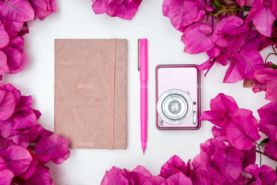 My daily routine: plan my day, and take some photos!  Image of pink notebook pen and camera on white background with pink bougainvillea flowers.
