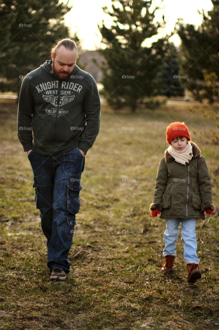 Little girl in a cap with fox ears walks in the park with dad