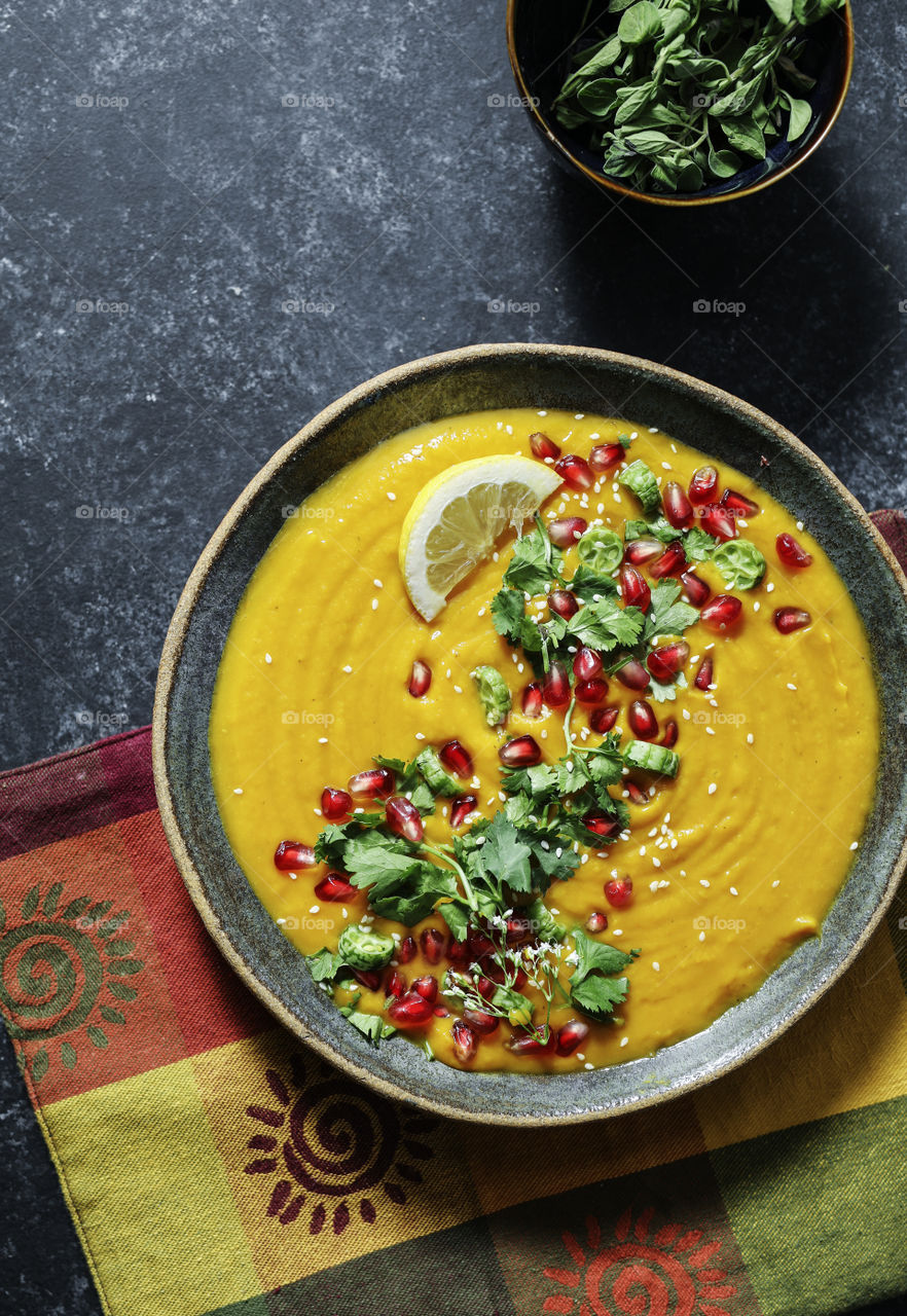 Fresh pumpkin soup topped with parsley and pomegranate seeds