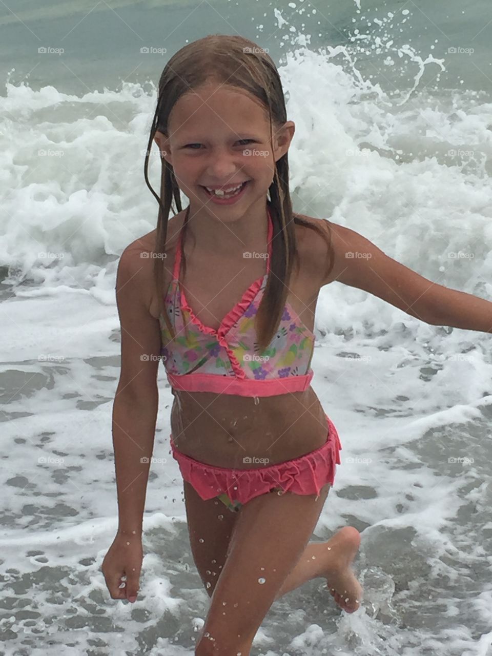 Little girl playing in the waves of the ocean